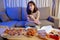 Young asian woman takeaway eating junk food unhealthy on couch watching tv series eatery fast food