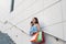 Young Asian woman taling on phone while standing on stairs with color bags