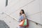 Young Asian woman taling on phone while standing on stairs with color bags