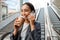 Young asian woman talking on cellphone and drinking coffee while standing on escalator