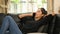 Young Asian woman is talking on a mobile phone while lying on the black leather sofa