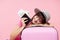 Young asian woman tourist with passport, plane tickets and pink suitcase on pink background.