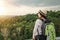 young asian woman traveler with backpack relaxing on mountian and looking forest