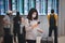 Young asian woman traveler using smartphone and holding luggage while waiting check-in at terminal in international airport due to