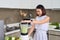 Young Asian woman using blender to make green smoothie in kitchen