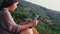 Young asian woman using digital tablet for drawing, sketching art design while sitting at hill near sea