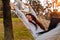 Young Asian Woman Using Laptop In Hammock In Autumn Park.