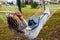 Young Asian Woman Using Laptop In Hammock In Autumn Park.