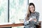 Young asian woman using smart phone while sitting by window cafe