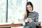 Young asian woman using smart phone while sitting by window cafe