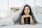 Young asian woman waking up at morning, Smiling woman resting under a duvet in her bedroom. Close Up portrait of a beautiful young