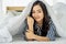 Young asian woman waking up at morning, Smiling woman resting under a duvet in her bedroom. Close Up portrait of a beautiful young