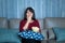 Young asian woman watching television suspense movie or news looking happy and funny and eating popcorn late night at home living