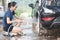 Young asian woman water spray her car with water tube washing it