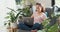 Young Asian woman wear casual calm sitting on wing chair use laptop computer thinking the idea for working full of plants in