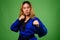 Young Asian woman wearing blue karate Gi against green backgroun