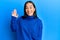 Young asian woman wearing casual winter sweater waiving saying hello happy and smiling, friendly welcome gesture