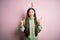 Young asian woman wearing cute easter bunny ears over pink background shouting with crazy expression doing rock symbol with hands