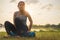 Young asian woman wearing exercise suit and sit on blue yoga mat or fitness mat after practicing yoga in park, Healthy concept,