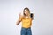 Young Asian woman wearing in yellow shirt is showing ok sign on white background, holding mobile phone, smiling,