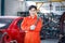 Young Asian worker in orange uniform looking at camera smiling. Skilled worker holding wrench on his shoulder working in auto