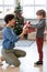 Young astonished female passing Christmas gift to her adorable little son