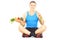 Young athlete on floor holding a dish full of fresh vegetables a