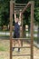 young athlete performing calisthenics exercises with hands through wooden bars placed in the garden