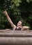 young athlete smiling and raising a hand pointing to the sky over wooden bars to perform handrail calisthenics exercises