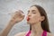 Young athlete woman drink water from plastic bottle while takes a break. Beautiful athletic girl In pink color