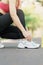 Young athlete woman tying running shoes with Energy Drink water, female runner ready for jogging outside, asian Fitness walking