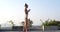 Young athlete woman in white sporty outfit on the roof over sky background