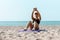 Young athlete on a yoga mat, with a slender body, working on the press, lying on the floor, training the press on the beach