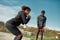 Young athletic african fitness couple in sportswear exercising together in the park, using resistance band outdoors
