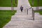 A Young Athletic Beautiful Girl Running Up The Stairs In A Green Park. A beautiful teenage girl in a jacket climbs up a stone