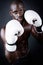 Young athletic boxer wearing gloves in black background.