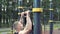 Young athletic couple doing pull-ups on the bar together outdoors