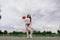 Young athletic female, in top and sweatpants, playing with ball on basketball court outdoors