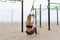 Young athletic fitness woman exercising doing suspension training with trx fitness straps on bars outdoor beach gym.Crossfit