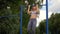 Young athletic fitness woman working out at outdoor gym doing pull ups at sunrise