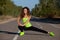 Young athletic girl in black-green tracksuit doing morning sports training in the park.