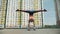Young athletic girl doing exercises handstand and holds the split. Training on the street. Fitness and stretching.