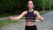 Young athletic girl engaged in fitness wearing black sportswear with a rubber band in her hands in a summer park. Girl