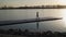 Young athletic girl goes down the pontoon along the lake on the background of beautiful sunset. Slow motion. Shooting on Steadicam