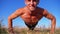 Young athletic man with a bare torso performs push-ups with claps on nature. Slow motion