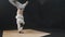 Young athletic man dancer spinning around leaning on his hands - training in the dark studio