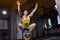 Young athletic man doing exercises in cross fit gym while crouching on two legs on the kettlebell.