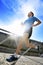 Young athletic man practicing running in urban background backlight in fitness sport training and healthy lifestyle concept