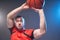 Young athletic man prepared for throwing basketball ball with lights on background