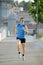 Young athletic man running on urban city park in summer sport training session